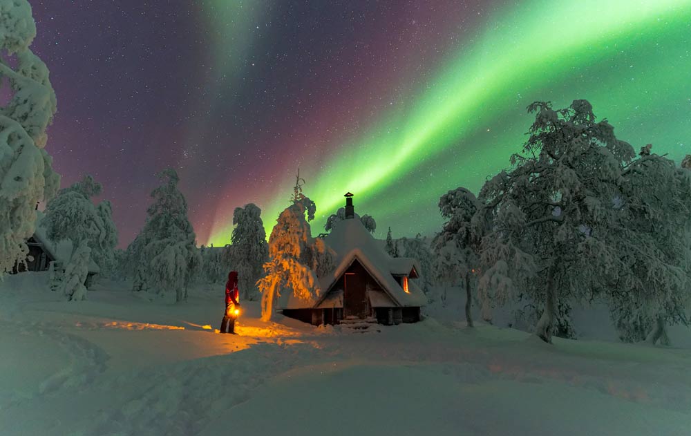 Polarlichter über einer verschneiten Blockhüte in Finnland