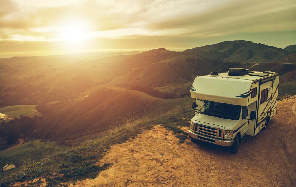 Camper auf einem Hügel bei Sonnenuntergang